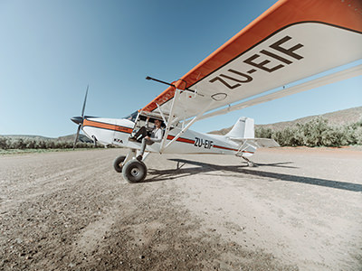 Bush plane pilot sitting in the backcountry plane parked on a natural terrain in South Africa, photo by Jared Watney, Unsplash.