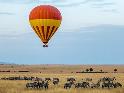 Hot air balloon flying over a zebra herd in Maasai Mara National Reserve in Kenya, photo by Sutirta Budiman, Unsplash.