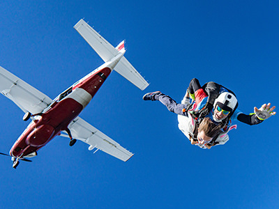 Skydiving tandem jumping out of the plane, shot from beneath, photo by Kamil Pietrzak, Unsplash.
