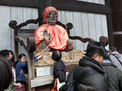 People at Todai-Ji Buddhist temple in Nara, Japan, touching the wooden statue of Binzuru or Pindola Bharadvaja, one of the Buddha's disciples that supposedly has occult powers. People believe that rubbing a part of the statue and then rubbing the corresponding part on own body will make ailment disappear; photo by Ivan Kralj.