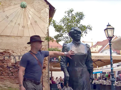 Croatian travel author Boris Veličan holding a breast of a statue representing the feminist journalist Marija Jurić Zagorka in Zagreb, hoping to launch a new good-luck seeking tradition of statue rubbing, screenshot HRT.