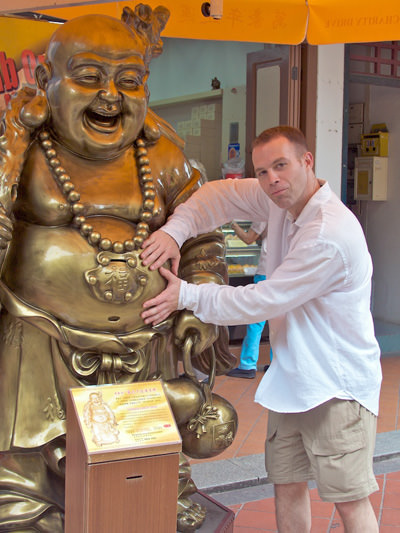 Man rubbing Buddha statue's belly, a ritual believe to secure luck and prosperity; photo by Brian Holsclaw.
