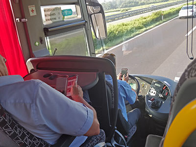Bus driver driving on a highway in Croatia, while using mobile phone with both hands. The co-driver sitting behind him is also on the phone; photo by Ivan Kralj.