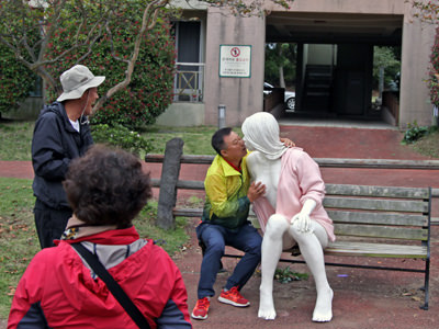 To amusement of his friends, a man is kissing and grabbing a female statue for a breast at Jeju Loveland, open-air sex museum in Jeju, South Korea; photo by Ivan Kralj.