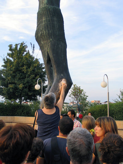 The female pilgrim rubbing the "wheeping knee" of the Risen Christ statue in Medjugorje. The knee produces drops of water believed to be miraculous healing properties; photo by Lsimon.