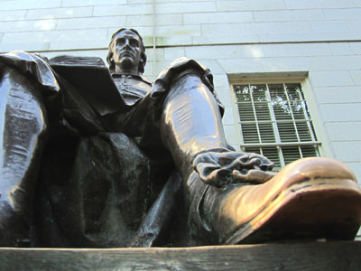 Golden-color shoe of the black bronze statue of John Harvard, the change as a result of frequent rubbing for good luck; photo by Wallyg.
