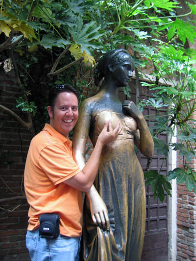 Man laughing while holding Juliet's breast in Verona for an imaginary nipple; statue rubbing in what is promoted as a courtyard of real-life Juliet cause damages on the monument over the years; photo by Docjelly.