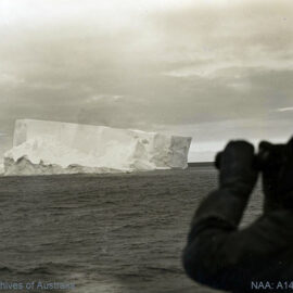 Man observing a tabular iceberg in Antarctica 1906-1937.