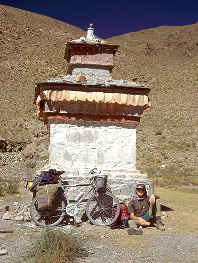 Slovenian travel photographer Matjaž Krivic sitting on the floor next to a bicycle in Tibet.