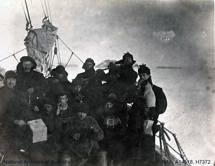 Men exploring Antarctica aboard a ship, posing with music instruments during the British Antarctic Expedition 1907-1909.
