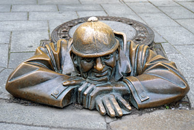 Statue of a plumber Chumil poking his head through the manhole in Bratislava, Slovakia. Passersby traditionally rub his head for good luck, photo by Archer 10 Dennis Jarvis.