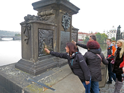 People queueing on Charles Bridge in Prague, Czech Republic, to touch the plaque of Saint John of Nepomuk. They believe this statue rubbing ritual will ensure their return visit to the town; photo by Baldeaglebluff.