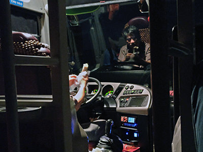 Vietnamese bus driver eating a spring roll with both hands during the night ride to Hoi An; photo by Ivan Kralj.
