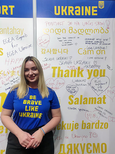Liza Konoplova, manager of international cooperation & partnerships at State Agency for Tourism Development of Ukraine, posing in front of the wall with visitors' messages at Place2Go fair in Zagreb, Croatia; photo by Ivan Kralj.