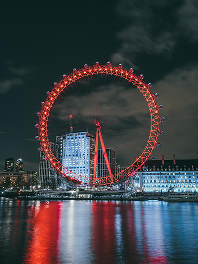 London Eye Ferris wheel, the largest cantilevered observation wheel in the world, lighted red on the South Bank of the Thames by night; photo by Chengdong Deng, Unsplash.