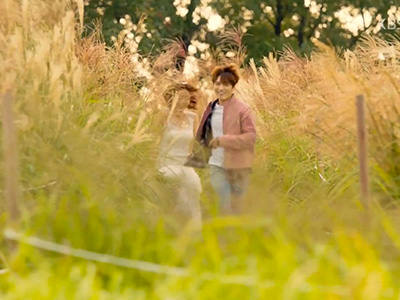 Screenshot from "Manhole" Korean drama (2017), of a couple running through the silver grass field at Haneul Park, Seoul, South Korea.