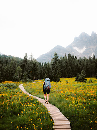 A backpacker hiking in Mount Assiniboine Provincial Park, Canada, with beautiful mountain landscape; photo by Devon Hawkins, Unsplash.