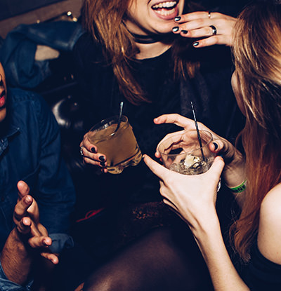 Women laughing, vividly gesticulating and having a drink in a club; photo by Michael Discenza, Unsplash.