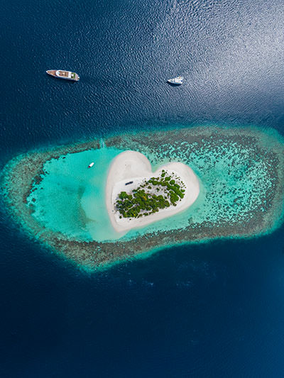 Viewed from above, a tropical sandy island in the Maldives that looks like a heart; photo by Vitaliy Sokol, Depositphotos.