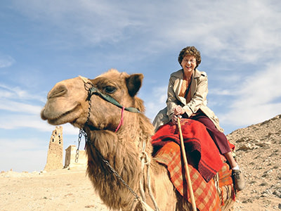 Sandy Hazelip, one of the TikTok Traveling Grannies, riding a camel in Syrian desert.