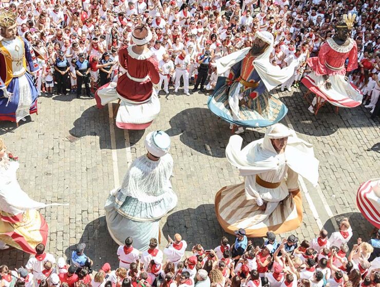 Giant puppets dancing on a street in Spain, surrounded by a lot of spectators; photo by San Fermin Pamplona - Navarra, Unsplash.