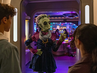 Rodian Ouannii with guests at Disney's Star Wars hotel Galactic Starcruiser; photo by Matt Stroshane, Disney Parks.