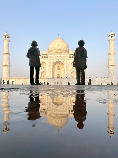 TikTok Traveling Grannies posing in front of Taj Mahal in India, with their reflection in water.