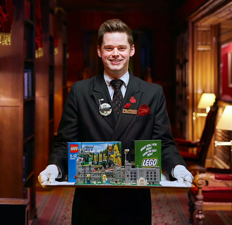 Lego butler at Ashford Castle hotel in Ireland, holding a silver tray with displayed Lego set, a special amenity of room service at their property.