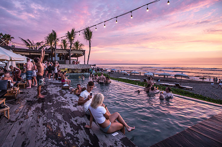People enjoying drinks at sunset at a pool party in Bali, Indonesia, destination struggling with unruly tourists and thus introducing new rules for visitors; photo by Cassie, Unsplash.