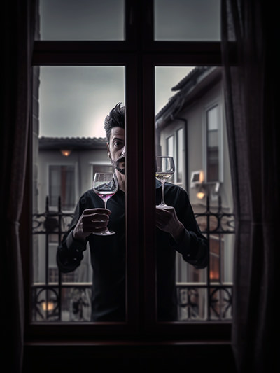 Creepy barman standing behind the balcony window and holding two glasses of wine; image by Ivan Kralj, Midjourney.