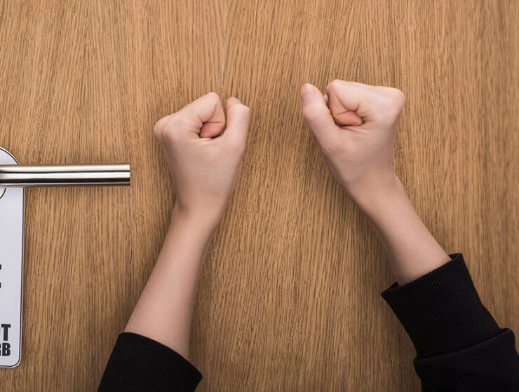 Hands knocking at the hotel door despite the 'Do Not Disturb' sign; photo by Vadim Vasenin, Depositphotos.