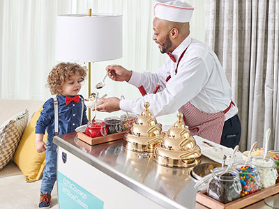 Ice Cream Man offering ice cream to a delighted young guest from his ice cream cart during the room service delivery at Four Seasons Hotel in Chicago, USA.