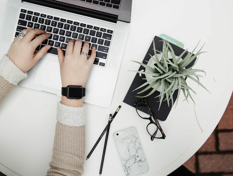 Person working on a laptop next to aloe vera plant, top view; blogxiety or blogging anxiety is experienced by 2 out of 3 bloggers; photo by Corinne Kutz, Unsplash.