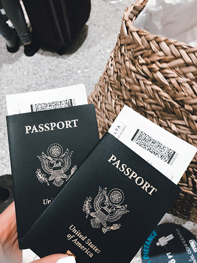 Hand holding passports with boarding passes at an airport; photo by Brianna R., Unsplash.