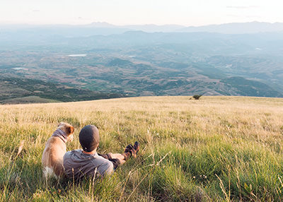Tom Turcich with his dog Savannah, lying in the grass and looking at landscape during their walk around the world.