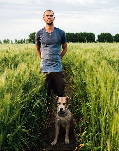 Tom Turcich standing in the field with his dog companion Savannah during their walk around the world.