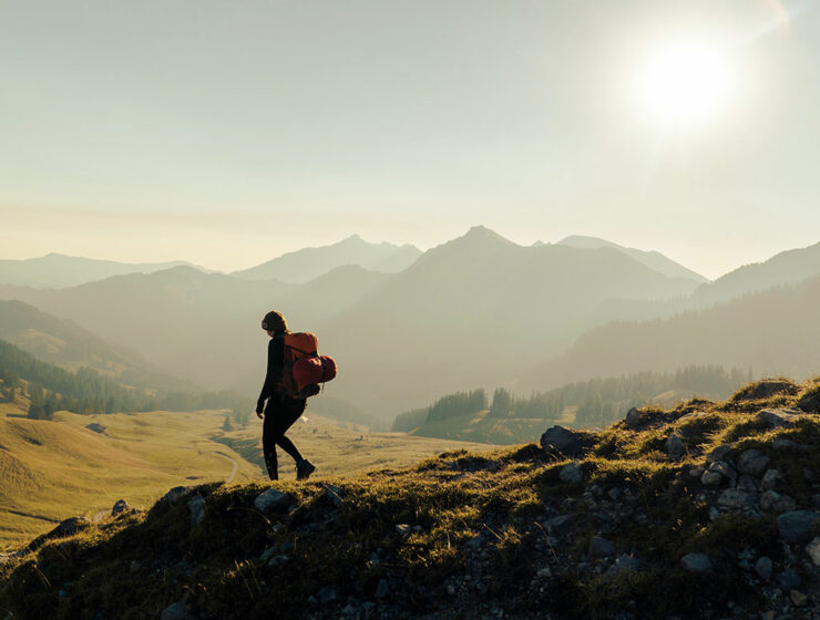 Backpacker walking in the misty mountainous landscape of the green Bernese Highlands, Swiss Alps; photo by Janis Fasel, Unsplash.