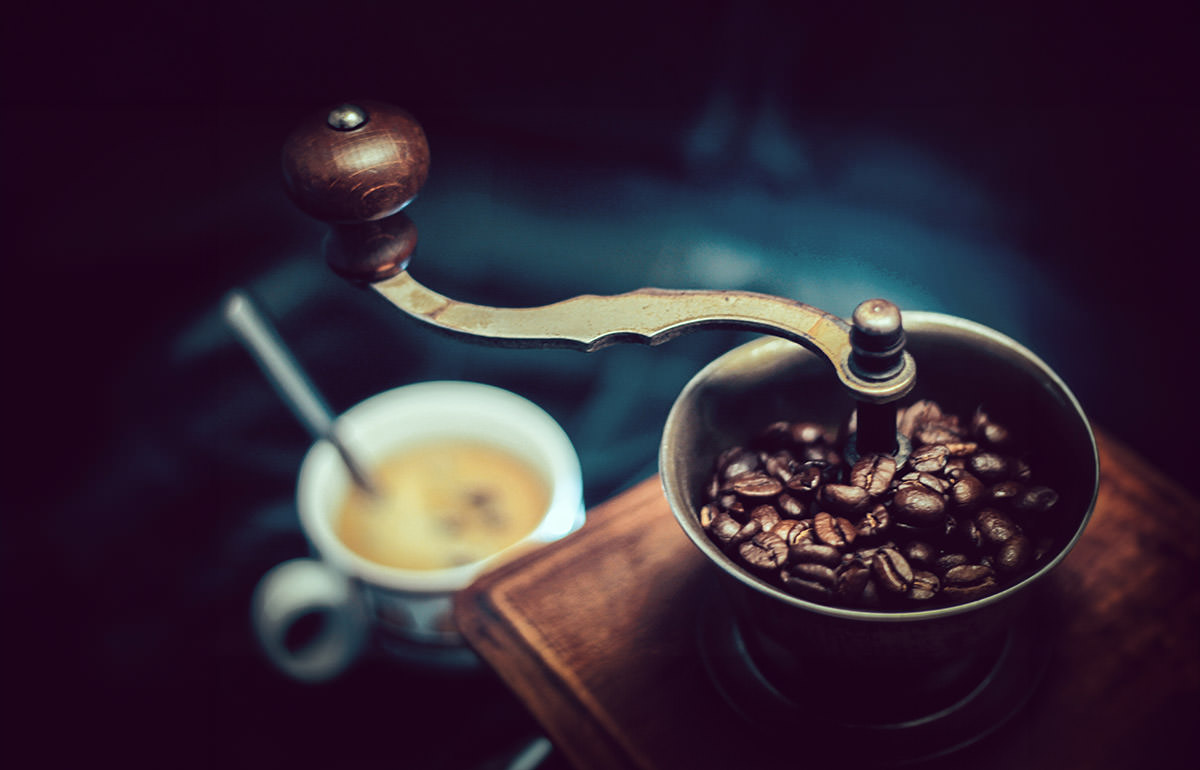 Vintage coffee grinder with a coffee cup in a blurred background - what are the best coffee destinations in the world?; photo by Tom Swinnen, Pexels.
