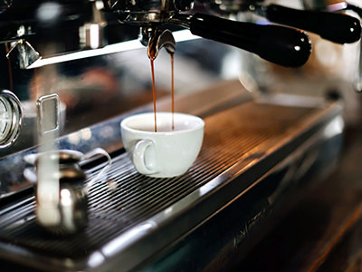Espresso coffee machine pouring coffeee into a cup; photo by Tabitha Turner, Unsplash.