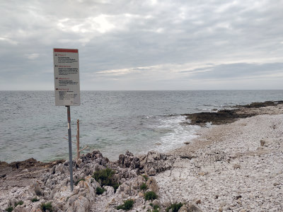 Signpost on Punta Križ FKK nudist beach in Monsena, Rovinj, Croatia, strictly prohibiting behavior "against public order and morals (exhibitionism, lewd acts, etc.); photo by Ivan Kralj.