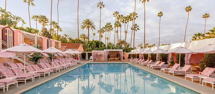 The Beverly Hills Hotel swimming pool with pink furniture and palms in the background; photo by The Beverly Hills Hotel.