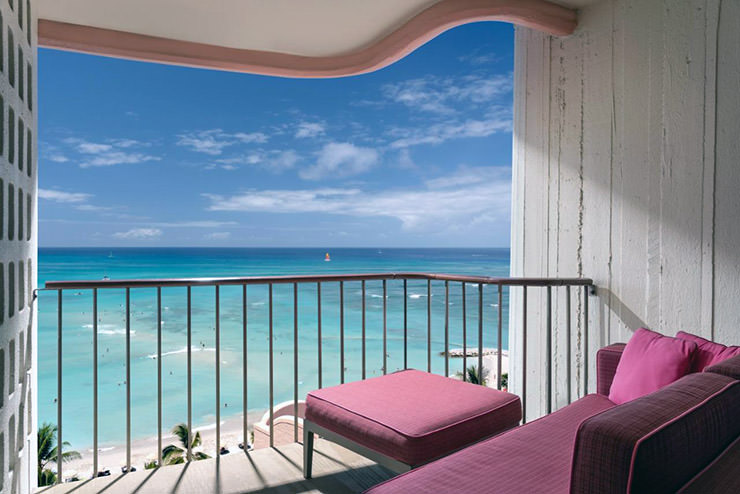The balcony view of the Pacific Ocean from The Royal Hawaiian hotel, with pink balcony furniture; photo by The Royal Hawaiian.