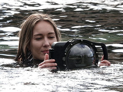 Young woman in water, filming with a camera in underwater housing GDome Mobile Pro Edition; photo by GDome.