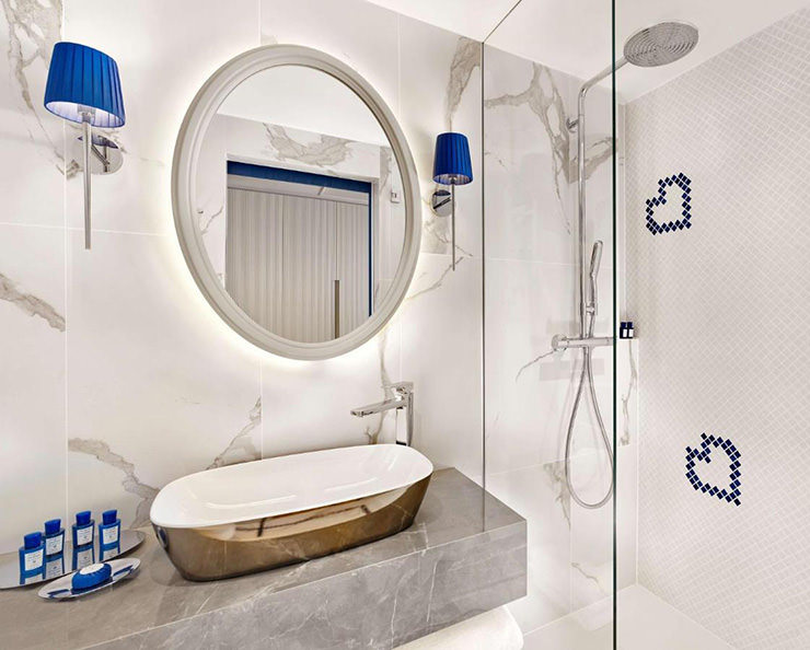 White marble bathroom with blue details such as tiles arranged in a shape of a heart, at Grand Hotel Brioni Pula, a superb hotel choice for couples on holidays in Croatia; photo by Grand Hotel Brioni Pula.