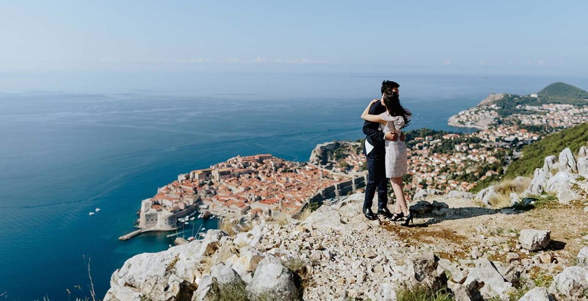 A couple on a honeymoon in Croatia, hugging with the panorama of Dubrovnik in the background; photo by Shevtsovy, Depositphotos.