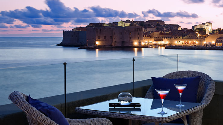 Drinks at the table at Abakus Piano bar at Hotel Ecelsior Dubrovnik terrace, with a panorama of night-time Dubrovnik in the background; photo by Adriatic Luxury Hotels.