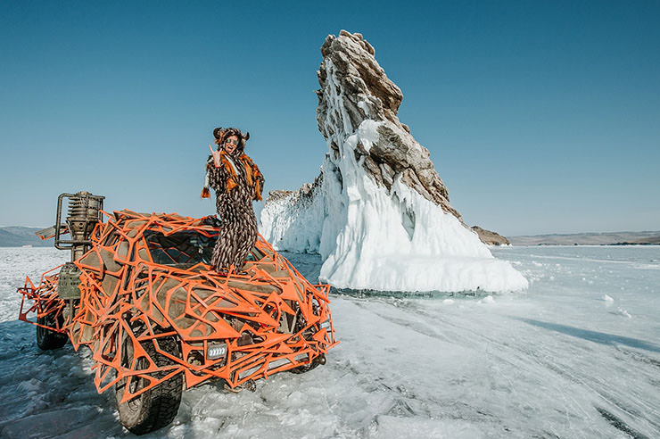 Woman in a furry costume, standing on an armored car in Mad Max style in the frozen landscape of Lake Baikal in Russia, during the MadWay Rally.