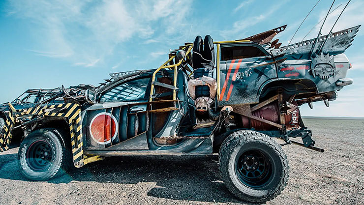A person hanging upside down from one of the modified cars in the fleet of MadWay Rally, Mad Max-inspired event organized by Alexey Gubarev.