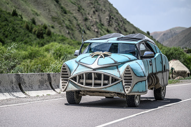 Retro-style post-apocalyptic blue car participating in MadWay Rally in Kyrgyzstan, event inspired by Mad Max universe.