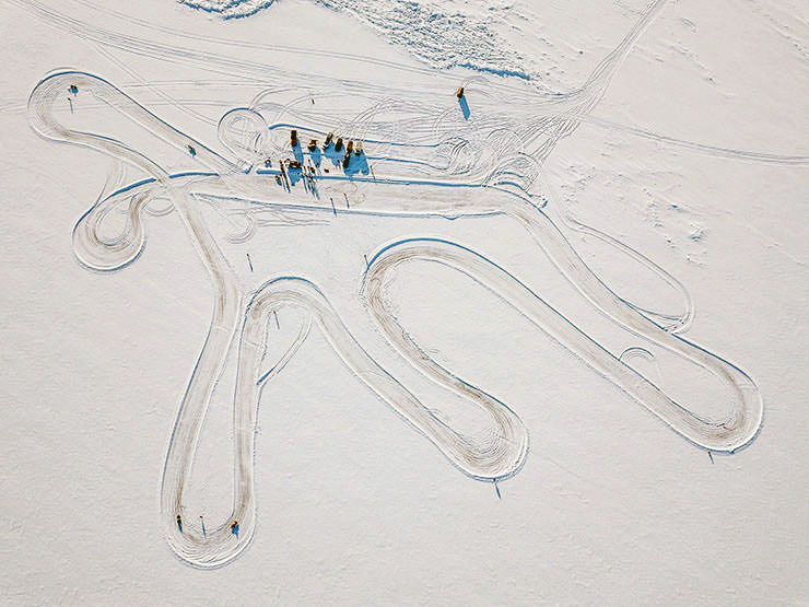 Aerial view of the winding trail left by the cars in the snowy landscape of the frozen Lake Baikal, during the MadWay Rally.
